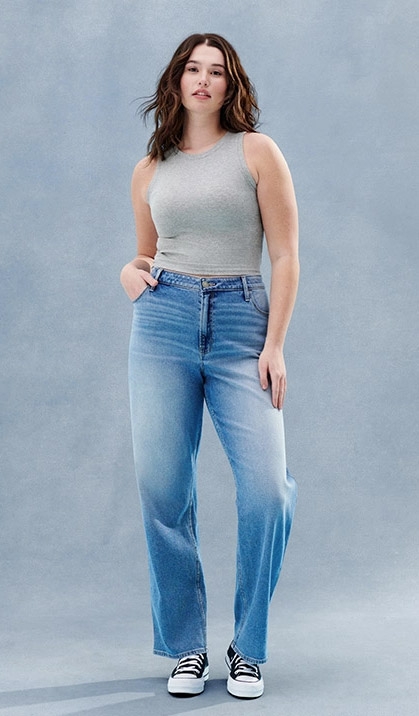 Young beautiful plus size model in blue jeans, xxl woman on gray background  Stock Photo